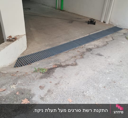 רשת מתכת על רצפת בטון ליד קיר לבן